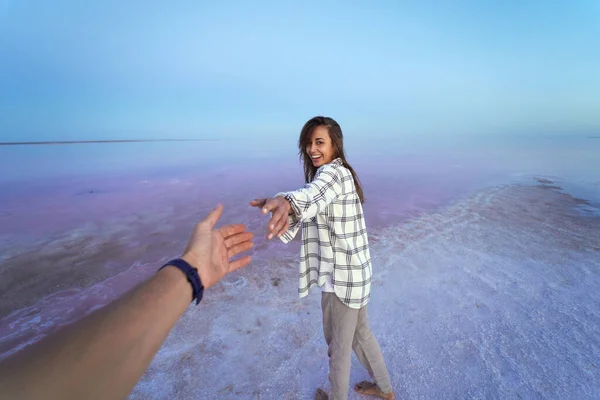 Vista en primera persona, POV chica feliz caminando en el colorido lago rosa, extendiendo la mano mans mano. Viajes domésticos, hermoso paisaje natural. — Foto de Stock