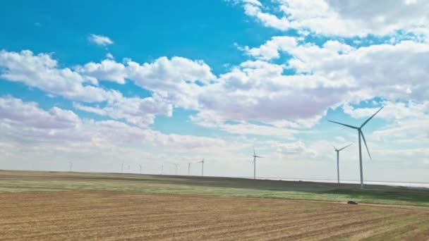 Samochód poruszający się rustykalną drogą na tle generatorów energii wiatrowej — Wideo stockowe