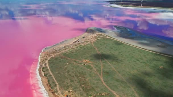 Vista aérea sobre hermoso paisaje colorido con costa de lago rosa y turbinas de viento en el fondo — Vídeo de stock