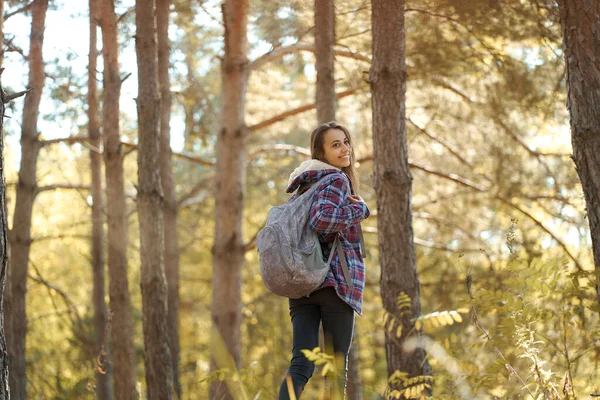 Tourist woman with backpack in forest, smiling and turning around to camera. — Stock Photo, Image