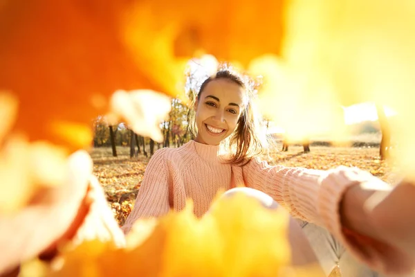 Iloinen hymyilevä tyttö tekee selfie kehyksestä noidan syksyn lehdet — kuvapankkivalokuva