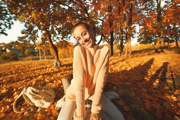 POV, første person ser en glad kvinne i koselig genser ved sollys høstpark - bitende bladverk – stockfoto