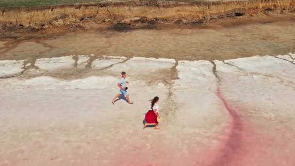 Bella giovane coppia passeggiando lungo il bellissimo lago rosa con riva salata — Video Stock