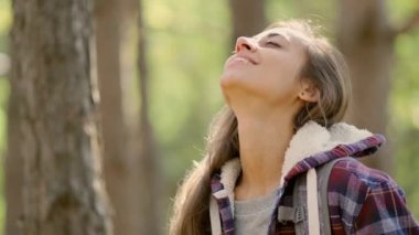 Sırt çantalı bir turist kadın ormanda kollarını açıp sonbahar sezonunun tadını çıkarıyor..