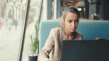 Düşünceli kadın dikkatle dizüstü bilgisayarda çalışıyor.