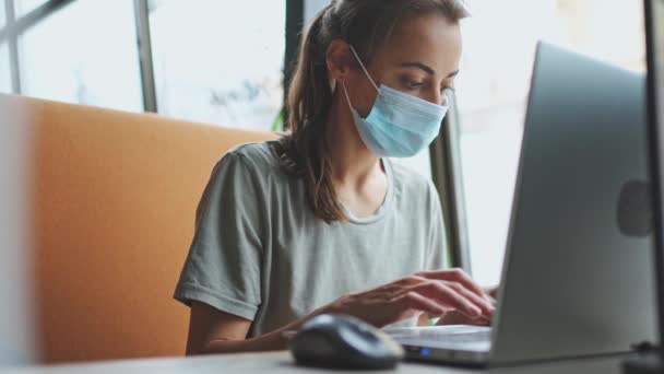 Vrouw in medische beschermende ademhalingsmasker werken op laptop — Stockvideo