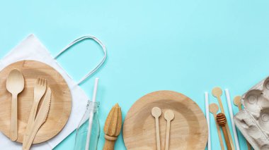 Çevre dostu market çantası, ahşap çatal bıçak takımı, cam şişe, mavi arka planda yumurta kutusu. Kavram-çevre dostu sıfır atık plastiği. Uzayı metin için kopyala. Üst manzara, düz uzanma.