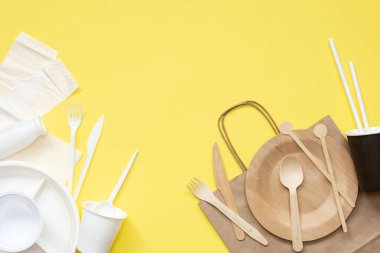 Sarı arka planda plastik ve ahşap kaplar. Çevre dostu aletler seçiyorum. Kavram: Çevrenin korunması. Plastik alternatif. Sıfır.