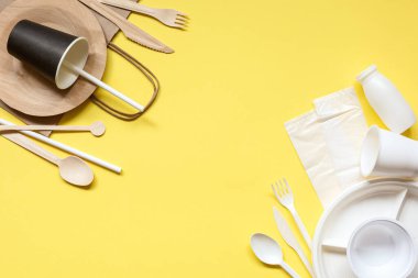 Sarı arka planda plastik ve ahşap kaplar. Çevre dostu aletler seçiyorum. Kavram: Çevrenin korunması. Plastik alternatif. Sıfır.