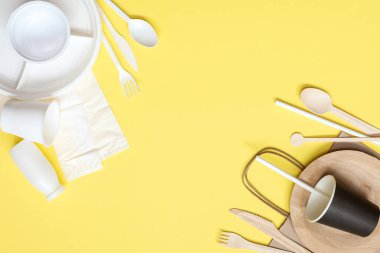 Sarı arka planda plastik ve ahşap kaplar. Çevre dostu aletler seçiyorum. Kavram: Çevrenin korunması. Plastik alternatif. Sıfır.