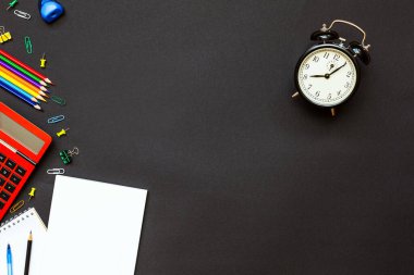 Okul konseptine geri dönelim. Okul malzemeleri siyah arka plan ve çalar saat üzerine. Üst Manzara. Metnin için alanı kopyala. Düz la