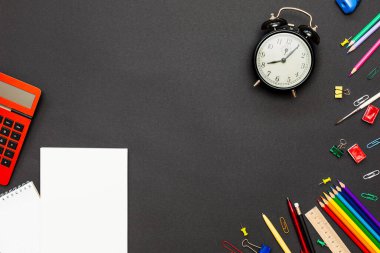 Okul konseptine geri dönelim. Okul malzemeleri siyah arka plan ve çalar saat üzerine. Üst Manzara. Metnin için alanı kopyala. Düz la