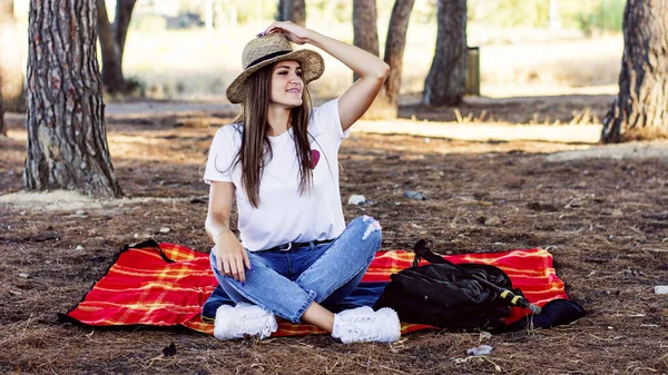 秋の日に帽子をかぶった若い女性が畑の毛布の上に座っている姿 — ストック写真