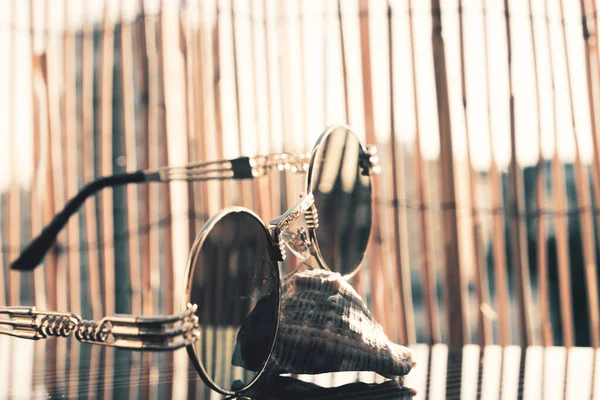 Dışarıda bambu arka planda yuvarlak mercekli klasik güneş gözlüğü modeli. Seçici odak 