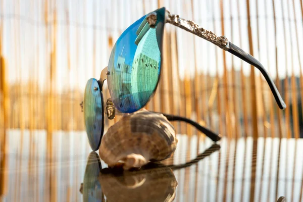 Ochelarii de soare cu lentilă albastră stau pe masă cu backgrpund de bambus. Model ochi de pisică pentru doamne closeup. Focalizare selectivă — Fotografie, imagine de stoc