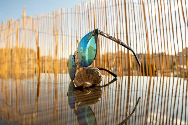 Óculos de sol com lente azul sentar-se na mesa com backgrpund de bambu. Modelo de olho de gato para senhoras close-up. Foco seletivo — Fotografia de Stock