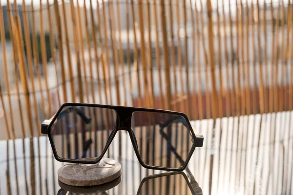 Aviator solglasögon med stora linser för män sitta på bordet med bambu staket bakgrund. Selektiv inriktning — Stockfoto