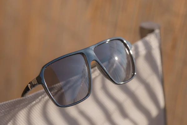 Ρετρό αεροπόρος γυαλιά ηλίου μοντέλο με μαύρους φακούς και μαύρο πλαίσιο πλαστικό υλικό που αντανακλά τον ήλιο σε ένα κοντινό πλάνο καλοκαιρινής ημέρας. Επιλεκτική εστίαση — Φωτογραφία Αρχείου