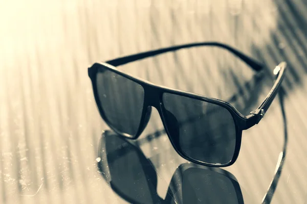 Retro aviator sunglasses model with black lenses and black frame plastic material reflecting the sun in a summer day closeup . Selective focus — Stock Photo, Image