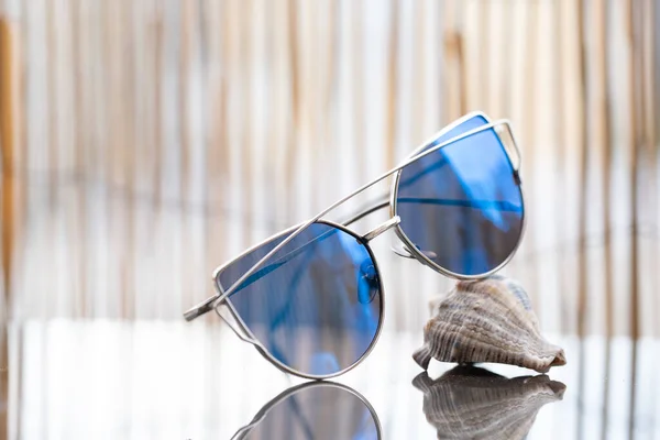 El perfil del modelo de gafas de sol Cat Eye para damas con lentes azules permanece en una concha que refleja el sol. Enfoque selectivo — Foto de Stock