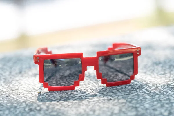 Κόκκινα pixel γυαλιά ηλίου με μαύρους φακούς από κοντά σε μια ηλιόλουστη μέρα. Επιλεκτική εστίαση — Φωτογραφία Αρχείου