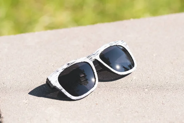 Occhiali da sole modello classico con lenti nere e montatura bianca in un primo piano giornata di sole. Focus selettivo — Foto Stock