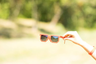 Güneşli bir günde siyah lensli kırmızı güneş gözlüğü pikseli model. Seçici odak