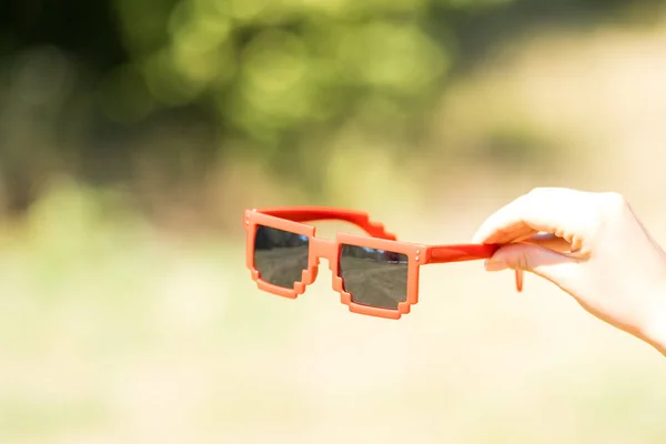 Red sunglasses pixel model with black lenses closeup in a sunny day. Selective focus