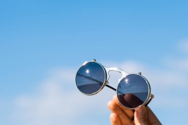 Steampunk güneş gözlükleri, yuvarlak lenslerle el ele tutuştu. Eski model yakın çekim, yaz günü çekildi. Seçici odak