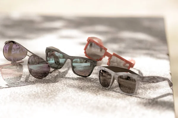 Collection of multiple sunglasses models for men and women stay on a table in a sunny day. Selective focus