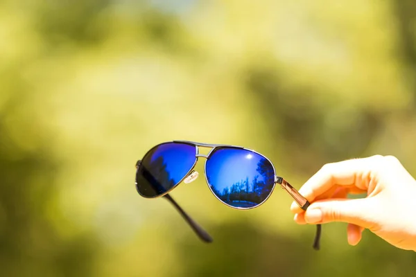 Модель ретро-авиатора в солнцезащитных очках держится вручную в летний день крупным планом. Селективный фокус — стоковое фото