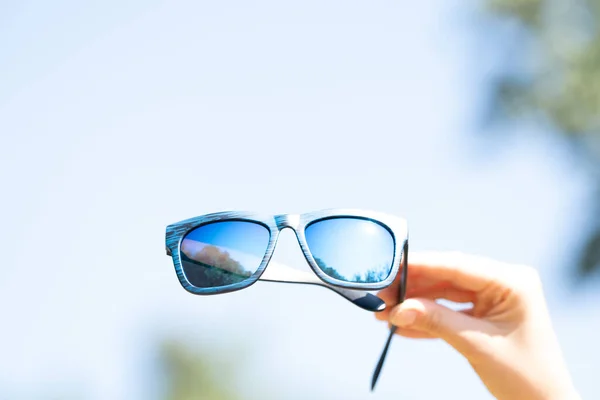 Modelo de gafas de sol retro con lentes azules que sostienen a mano el primer plano. Enfoque selectivo — Foto de Stock