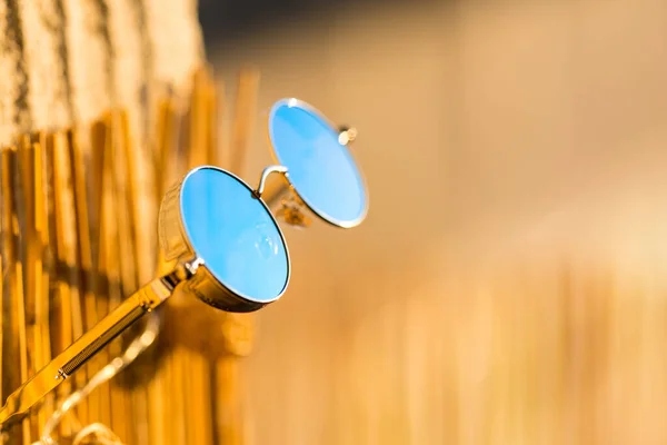 Модель солнцезащитных очков Steampunk с круглыми линзами, висящими на бамбуковом заборе в летний день крупным планом. Селективный фокус — стоковое фото