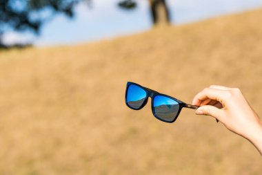 Mavi lensli klasik güneş gözlüğü modeli bir yaz günü yakın planda çekiliyor. Seçici odak