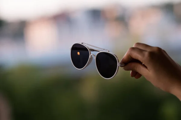 Retro aviator sunglasses model with big black lenses hold by hand in a summer day closeup . Selective focus — Stock Photo, Image