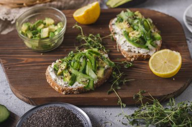Lezzetli taze peynir, taze gevrek ekmek arası peynir avokado ve salatalık ve üstte sağlıklı tohum