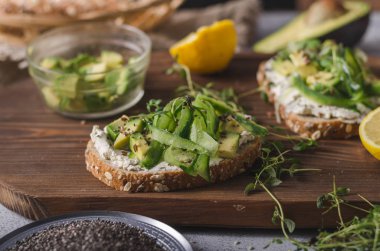 Lezzetli taze peynir, taze gevrek ekmek arası peynir avokado ve salatalık ve üstte sağlıklı tohum