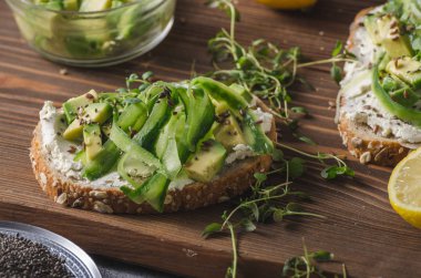 Lezzetli taze peynir, taze gevrek ekmek arası peynir avokado ve salatalık ve üstte sağlıklı tohum