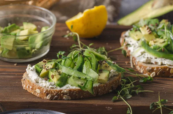 Delish fresh cheese on crisp bread, fresh cheese with avocado and cucumber and healthy seeds on top