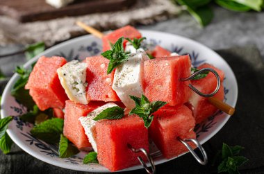 Feta ve mavi peynirli taze kavun, otlarla kaplı.