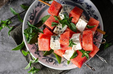 Feta ve mavi peynirli taze kavun, otlarla kaplı.
