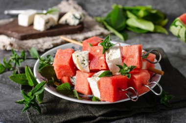 Feta ve mavi peynirli taze kavun, otlarla kaplı.