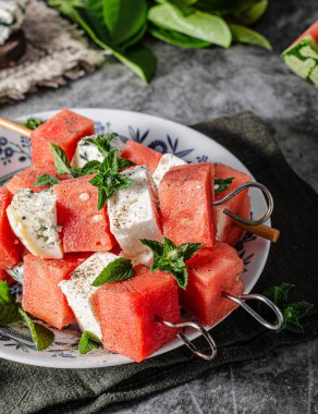 Feta ve mavi peynirli taze kavun, otlarla kaplı.