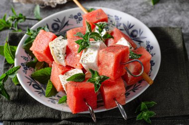 Feta ve mavi peynirli taze kavun, otlarla kaplı.