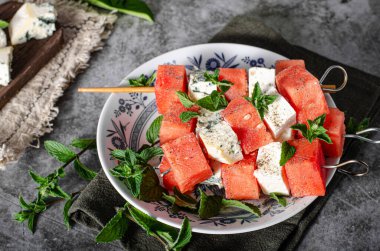 Feta ve mavi peynirli taze kavun, otlarla kaplı.