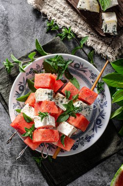 Feta ve mavi peynirli taze kavun, otlarla kaplı.