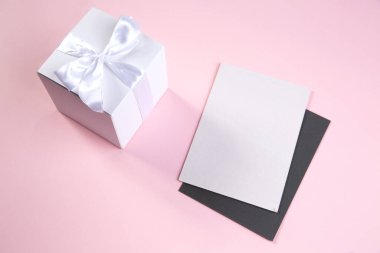 Tatil için beyaz hediye kutusu ve tebrik kartı. hassas pembe arkaplan.