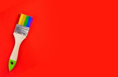 kırmızı arkaplanda gökkuşağı renkli tüyleri olan bir fırça. Üst Manzara. Metin için boşluk.