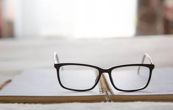 Image of an open notebook placed in bed with glasses at the top — Stock Photo, Image