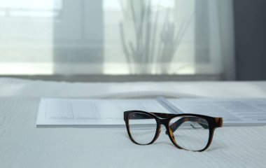 Yatağa yerleştirilmiş, gözlüklü, bulanık bir defter resmi. 
